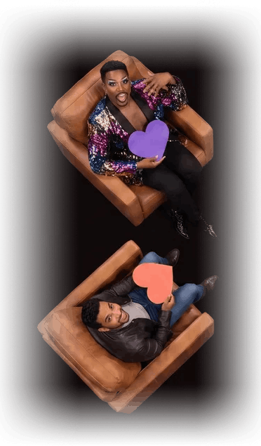 Two contestants seated in leather armchairs holding paper hearts
