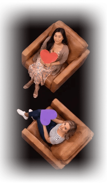 Two more contestants seated in leather armchairs holding paper hearts